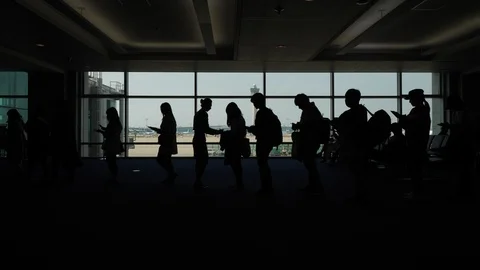 Queue move to boarding gate, airline staff check tickets, silhouetted Stock Footage 126939887