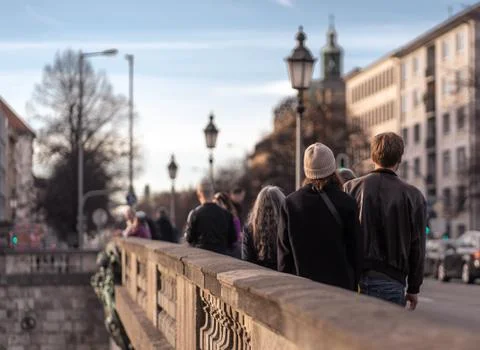 A queue of people standing on a bridge surrounded by buildings under the sunl Stock Photos