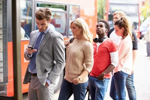 Queue of people waiting at bus stop Stock Photos