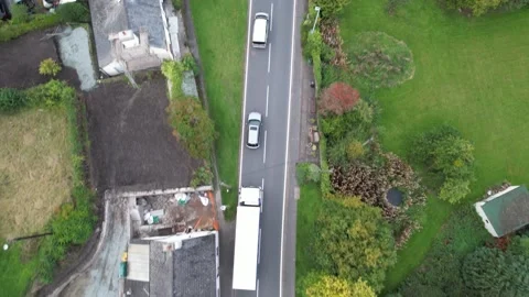 Queue of slowly moving vehicles on road in village Stock Footage 166693444
