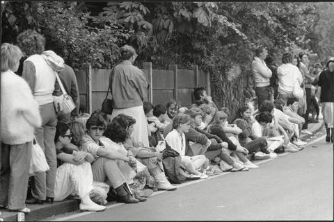 A Queue Of Tennis Fans Sit On The Ground As They Wait For The 1985 Wimbledon Ten Foto stock
