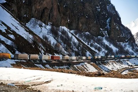 A queue of trucks in the snow-capped mountains is waiting for the pass to be  Stock Photos