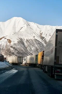 A queue of trucks in the snow-capped mountains is waiting for the pass to be  Stock Photos