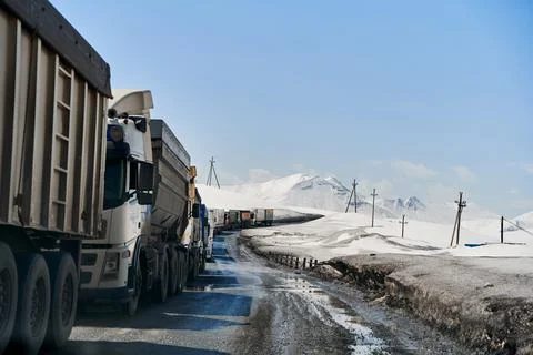 A queue of trucks in the snow-capped mountains is waiting for the pass to be  Foto stock