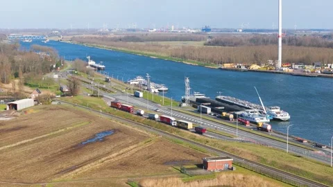 Queued trucks loaded barges mark active transport links wind turbines port Video stock 329069427