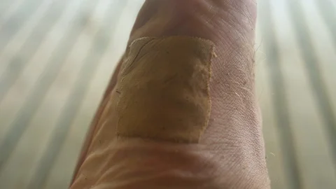 Quick and dirty improvise plaster protects cut on male foot Stock Footage 107904246