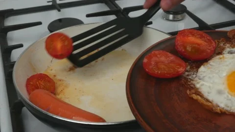 Quick breakfast - a man puts an egg and tomatoes with sausage from a frying p Stock Footage 134309625