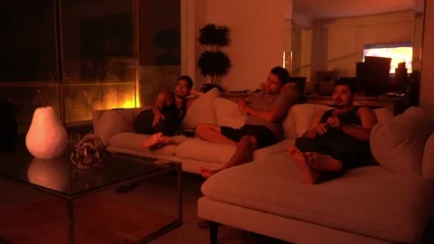 Quick camera of friends sitting on the couch in the living room watching a movie Stockbeeldmateriaal 192957667