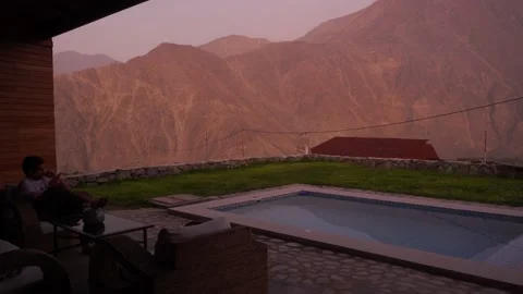Quick camera of a man looking at his cell phone sitting on the terrace of a coun Stock Footage 199578578