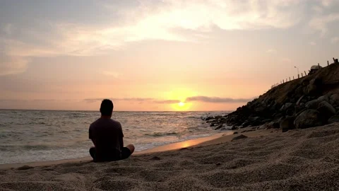 Quick camera of a man sitting on the sand looking longingly at the sea with the Stock Footage 195962856