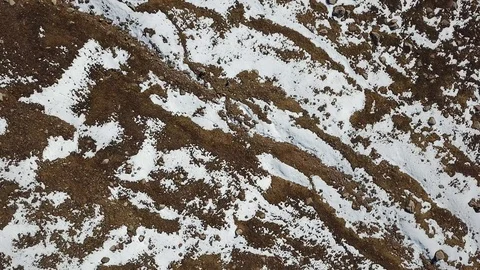 A quick descent down the drone. View of snow, relief land, yellow grass Vídeos de archivo 116590554