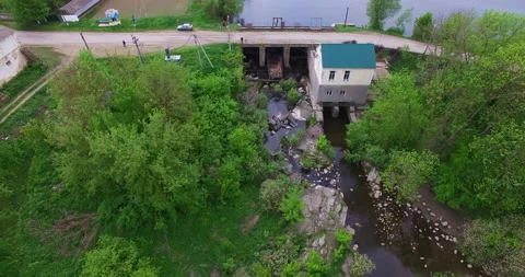Quick flight over the narrow river with green banks, dam over it. Video stock 211828183