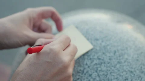 Quick handwritten note on textured urban park bench surface. Fingers scribbling Stock Footage 335071415