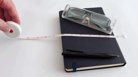 Quick Measurement: Notebook, Glasses, and Tape Measure Demonstration Stock Footage 313117285