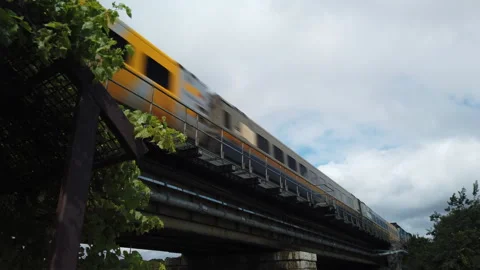 Quick moving Via Rail train passing over a railway bridge, low angle wide shot Stock Footage 308689800