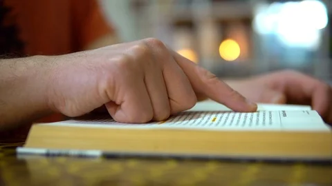 Quick read. A finger moves along the lines of a book. The guy turns the pages of Stock Footage 127349999