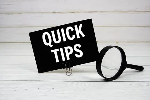 Quick Tips text message on paper card with magnifying glass on wooden backg.. Stock Photos
