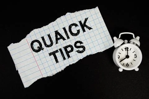 Quick Tips text written on paper with alarm clock on black background Stock Photos