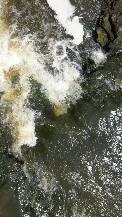 Quick vertical drone up over a small waterfall Video stock 246717519