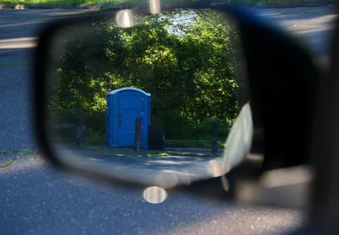 A quickly passing reflection of a porta potty in your car`s side mirror is no Stock Photos