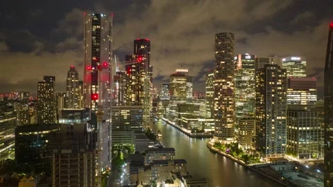 Quickly running clouds above illuminated futuristic Canary Wharf district Vídeos de archivo 202020986