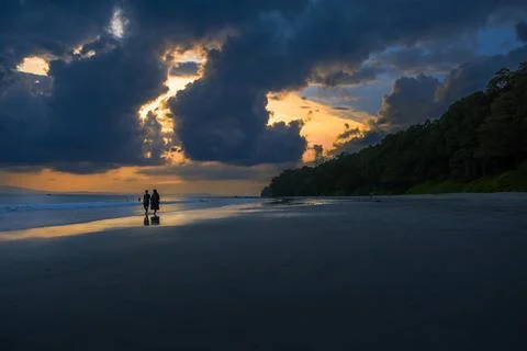 Quiet beach, dramatic sunset with cloud reflections on wet sand Stock Photos