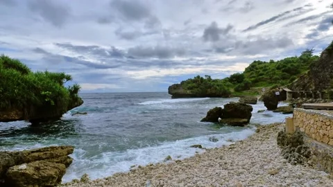 Quiet beach scene with calm waves and green rocky hills Video stock 166373381