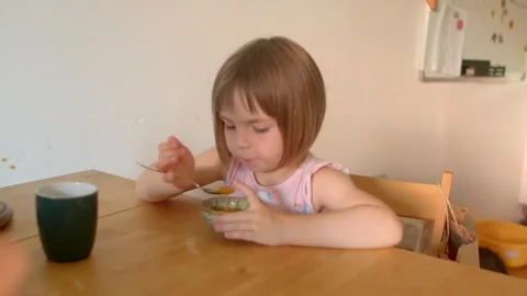 Quiet child considers breakfast with cautious and selective expression Stock Footage 320958254