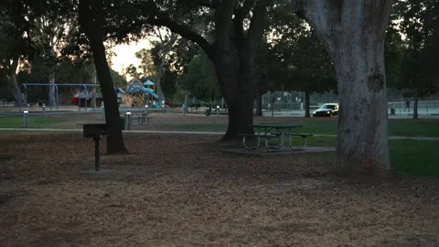 Quiet empty city park with picnic tables and playground at sunset Видео 331231226