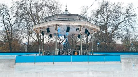 Quiet empty ice rink in winter decorated with Christmas lights and soft snow Stock Photos