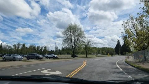 Quiet Eugene roadway borders an open parking area and broad grassy field Fotos de archivo