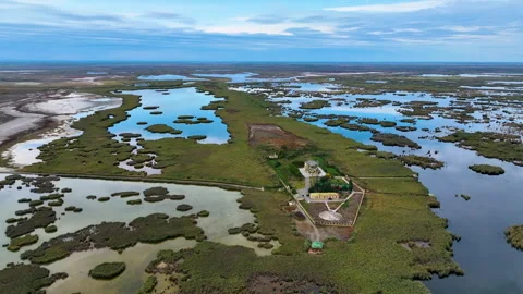A quiet lake surrounded by small grassy islands and a hotel building nearby Stock Footage 310663192
