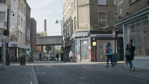 A quiet London street with pedestrians, passing train, delivery bike and car Stock Footage