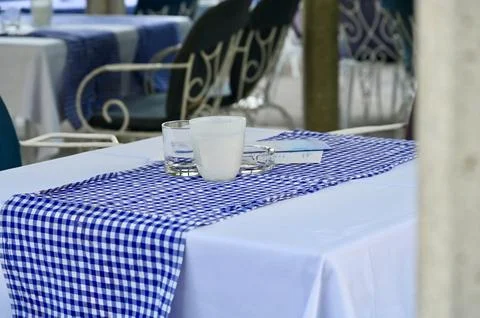 Quiet outdoor cafe table setting with glass and ashtray on checkered runner Stock Photos