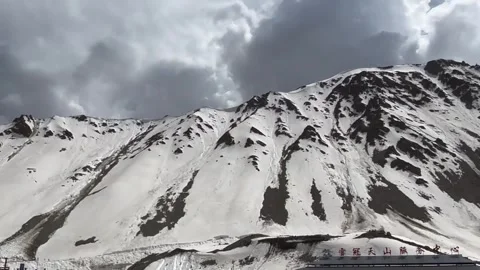 A quiet rest stop sits below a towering snow‑covered peak along Stockbeeldmateriaal 342577306