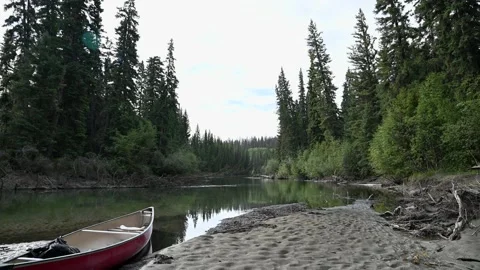 Quiet scene with a red canoe sitting on a sandy beach  Stock Footage 143786182