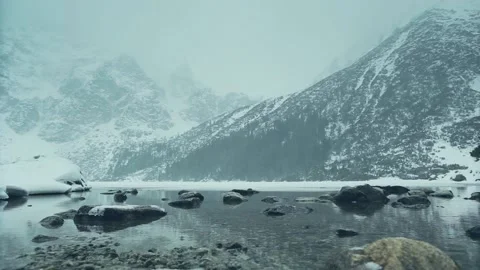  Quiet snow falls on the background of a lake and mountains. Stock Footage 101048516
