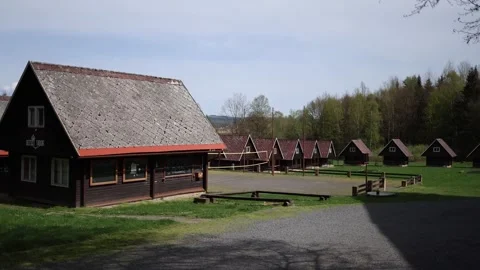 Quiet summer camp with rows of rustic wooden cabins stands empty under soft blue Video stock 307700174