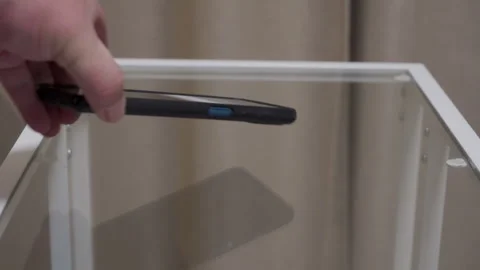 Quiet Thud: Hand Drops Black Cased Smartphone Gently onto Glass Table. Stock Footage 320809417