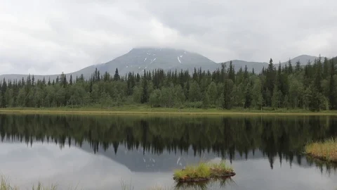 Quiet tranquil mountain lake. Reflection of green peaks in water Видео 93953866