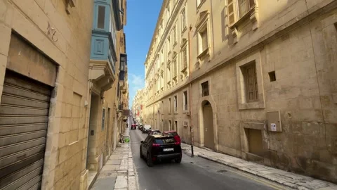 Quiet valletta side street parked cars tall limestone facades shuttered windows Видео 343676966