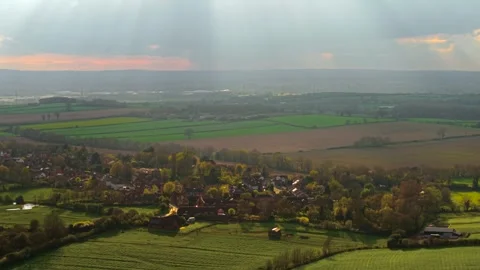 Quiet village surrounded by lush fields and trees with soft evening light over Stock Footage 332219194