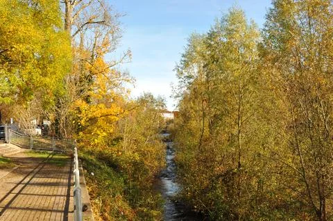 Quiet walking path lined with metal fencing beside peaceful river and vibra.. Stock Photos