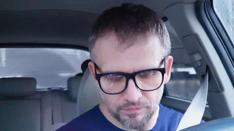 Quiet white man with beard driving car. Strong reflection in his glasses Stock Footage 124307315