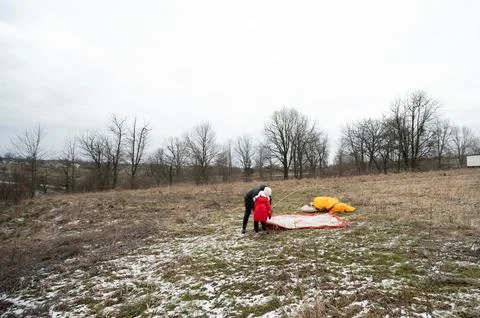 In a quiet winter setting, individuals work together to set up a parachute, s Stock Photos
