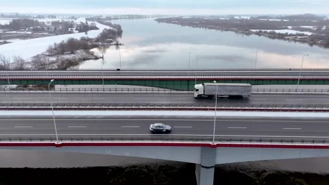 Quiet Winter Transit: Overpass Traffic Over a Serene Snowy Riverside Stock Footage 258142681