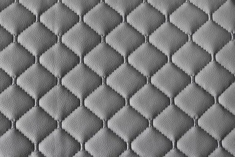 Quilted fabric pattern. The texture of the sofa is gray eco leather. Decorative Stock Photos