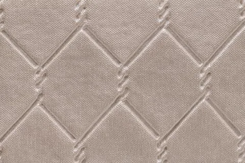 Quilted fabric texture with a diamond pattern in beige color, featuring a s.. Foto stock