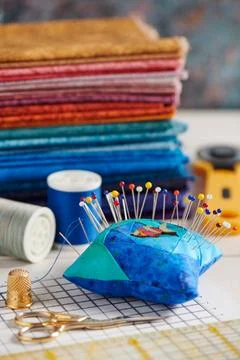 Quilting accessories on the background of a stack of bright quilting fabrics Fotos de archivo