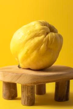 Quince fruit on a wooden tiny table on yellow background Stock Photos